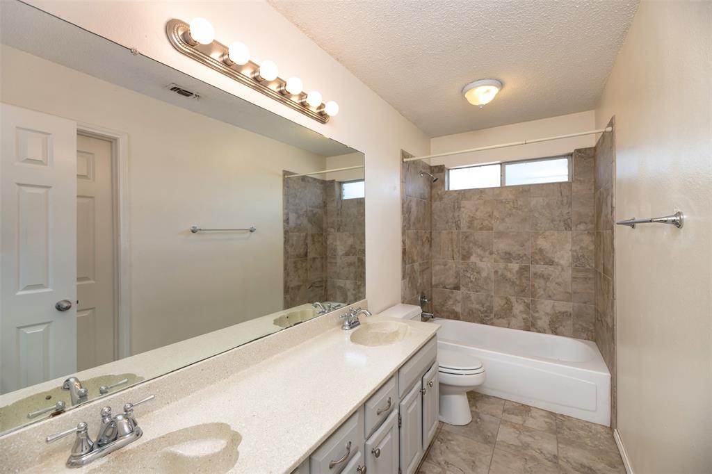 1410 Brookside Drive Allen, TX 75002 - Photo 26 of 38 a bathroom with a granite countertop sink a toilet a large mirror and shower