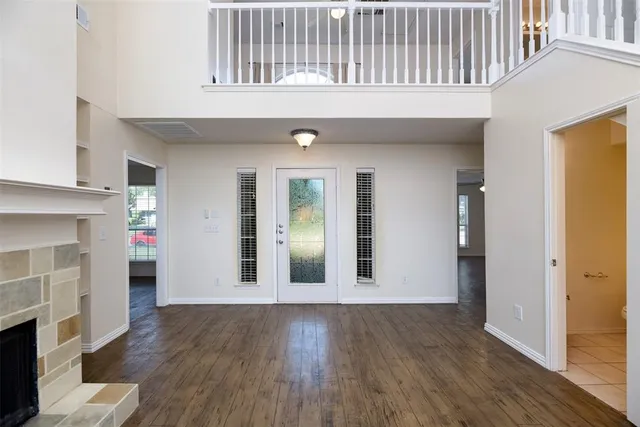 a view of an empty room with wooden floor and a fireplace