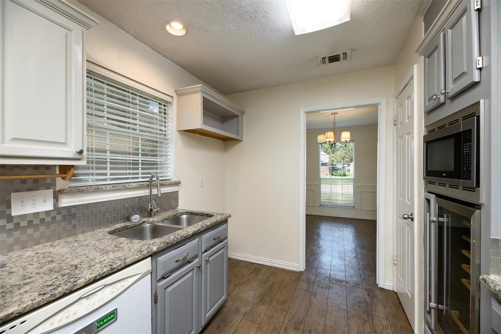 1410 Brookside Drive Allen, TX 75002 - Photo 7 of 38 a kitchen with a sink dishwasher a stove and a refrigerator with wooden floor