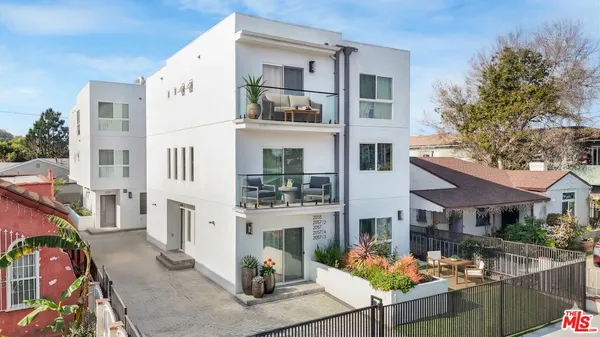 a front view of a house with outdoor seating and covered with potted plants