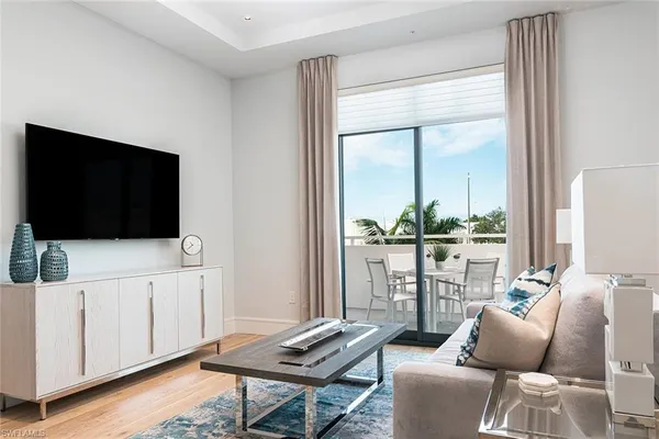 a living room with furniture a flat screen tv and a floor to ceiling window