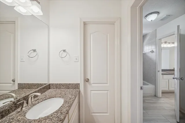a bathroom with a granite countertop sink a mirror and a shower