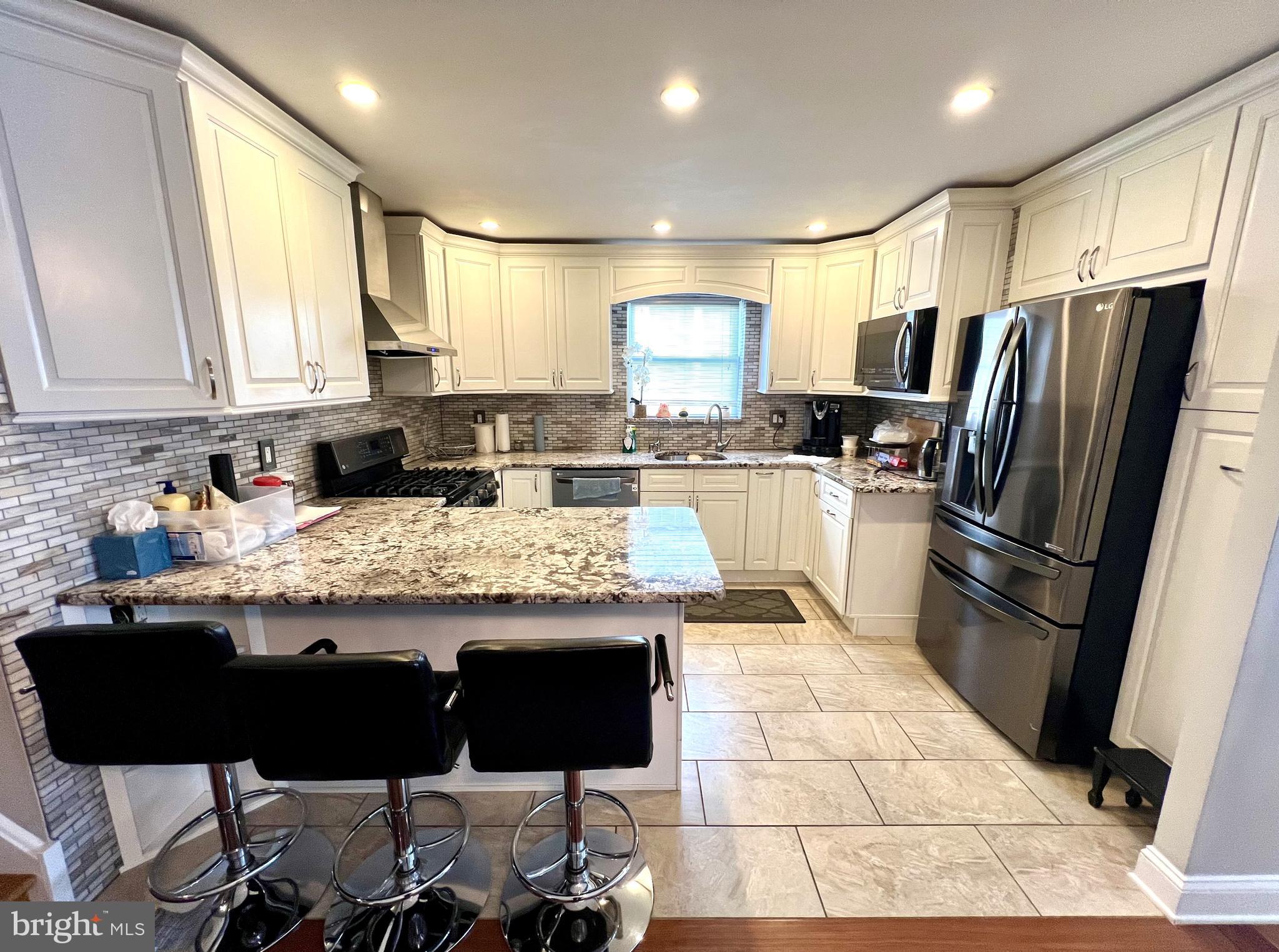 a kitchen with granite countertop a refrigerator and a stove top oven