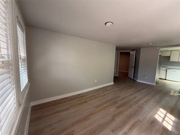 a view of an empty room with wooden floor and a window