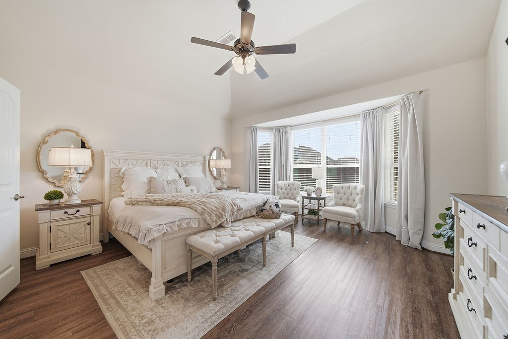 9614 Carson Lane Iowa Colony, TX 77583 - Photo 22 of 50 Bright, inviting bedroom with rich wood floors, a cozy sitting area framed by a bay window, elegant lighting, and direct access to a beautifully updated en-suite bath.