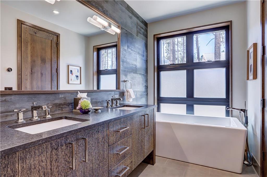 121 Boulder Circle Breckenridge, CO 80424 - Photo 21 of 35 a bathroom with a granite countertop sink a large mirror a bathtub and next to a window