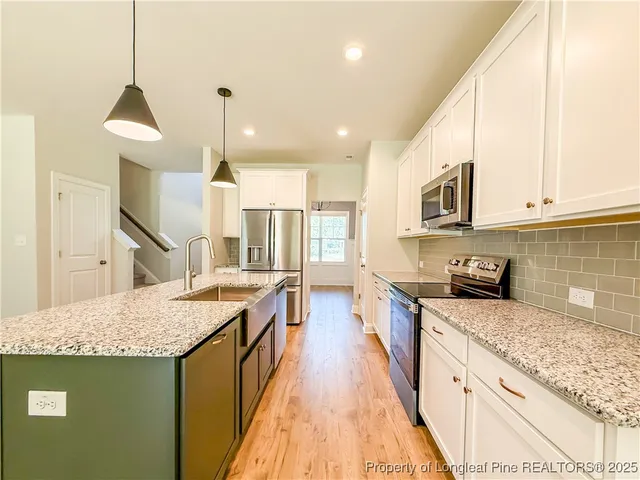a kitchen with stainless steel appliances granite countertop a sink a stove and a wooden floors