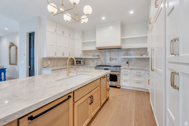 250 South Main Street, Unit 10 Alpine, UT 84004 - Photo 5 of 29 Gourmet kitchen featuring a large central island with integrated sink, stainless steel range with custom hood, extensive white cabinetry, light wood-finish flooring, and a contemporary chandelier