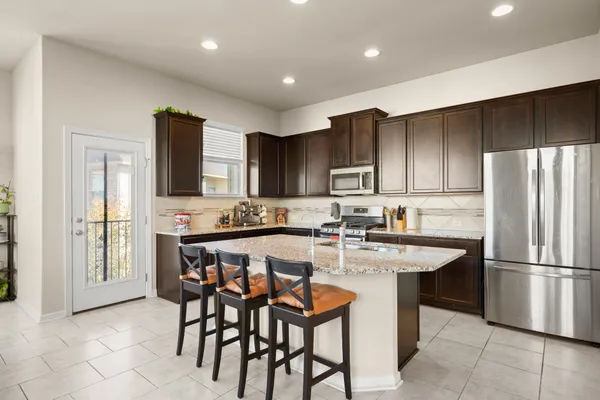 a kitchen with stainless steel appliances granite countertop a table chairs sink refrigerator and cabinets