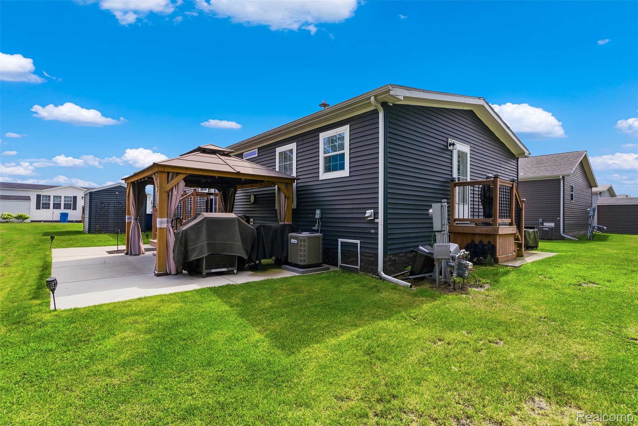 6450 Prince Boulevard Fenton, MI 48430 - Photo 27 of 31 Expansive green lawn surrounds a concrete patio featuring a gazebo with a fabric canopy