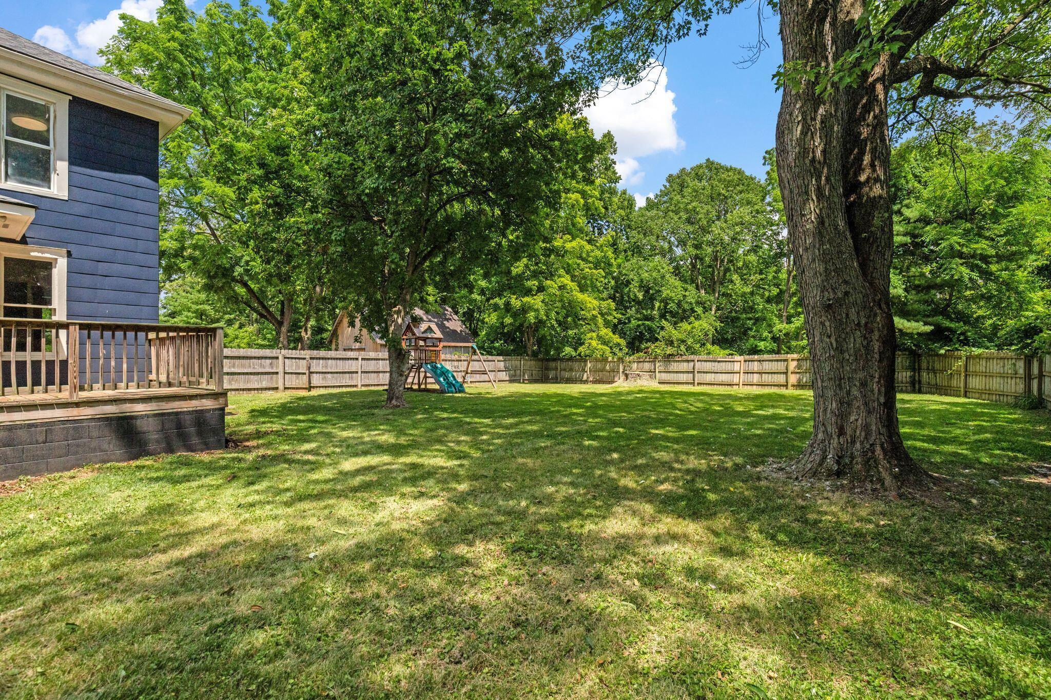 107 Price Road Columbus, OH 43230 - Photo 39 of 51 Expansive backyard featuring a lush lawn, mature trees, wood privacy fence, and a raised wooden deck