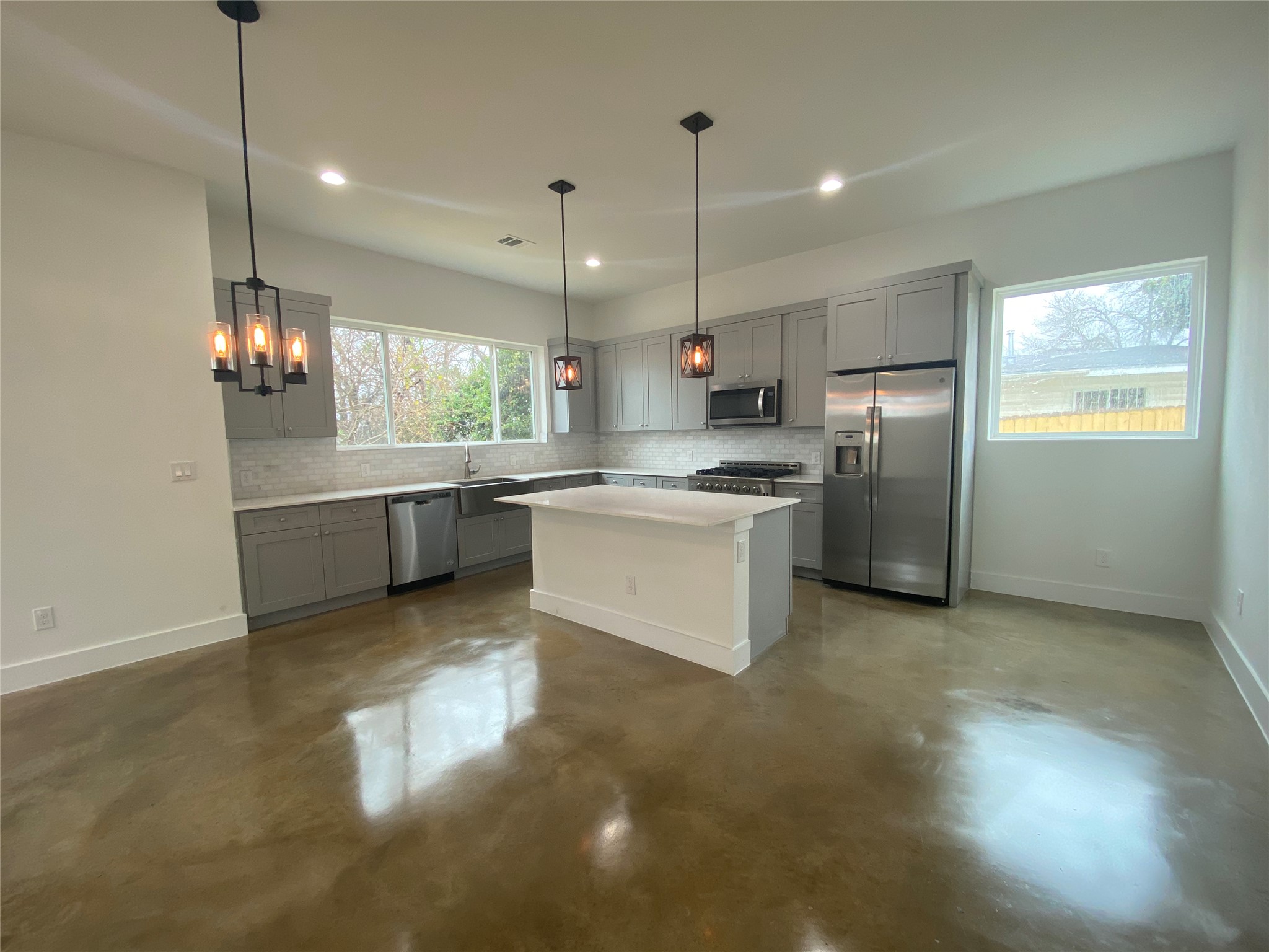 1916 Webberville Road, Unit B Austin, TX 78721 - Photo 5 of 25 Modern kitchen featuring an island, light gray cabinetry, stainless steel appliances, and a tiled backsplash