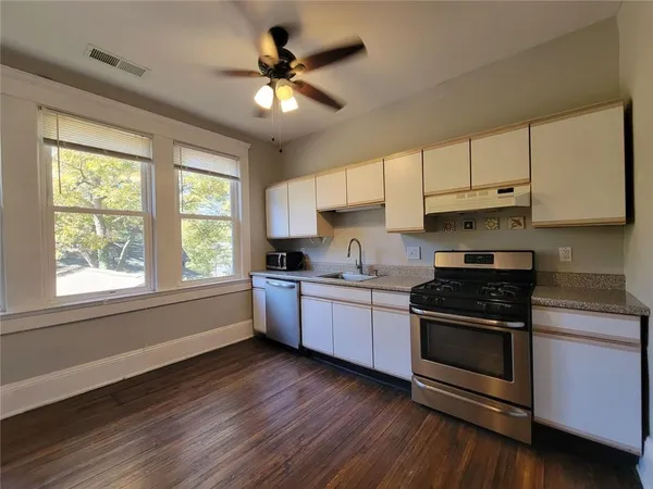 a kitchen with stainless steel appliances granite countertop a stove a sink and white cabinets