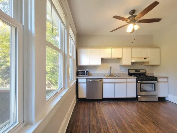 a kitchen with stainless steel appliances granite countertop a stove a sink and a large window