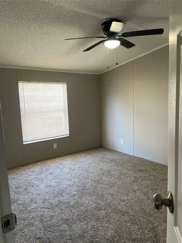 an empty room with a chandelier fan and windows