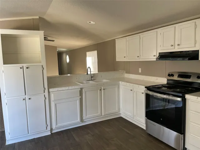 a kitchen with stainless steel appliances granite countertop white cabinets stove a sink and dishwasher