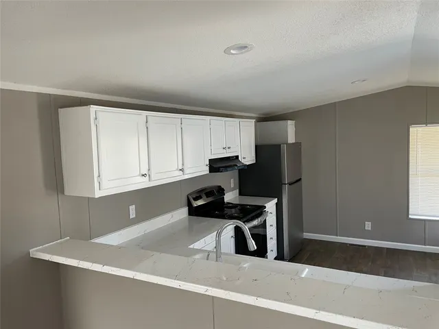 a kitchen with stainless steel appliances granite countertop a sink a stove a refrigerator a microwave and cabinets