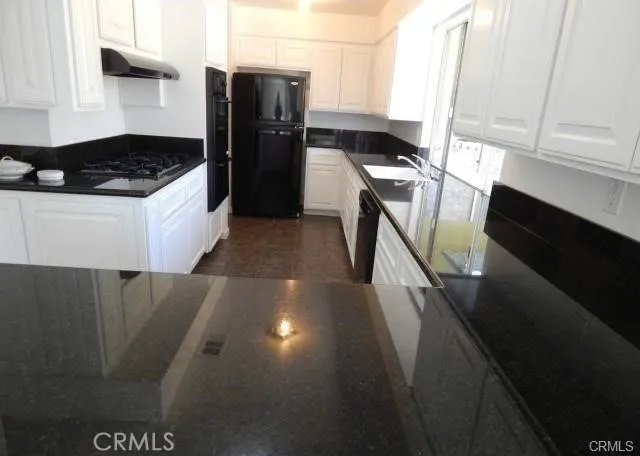 a kitchen with granite countertop a refrigerator a stove and a sink