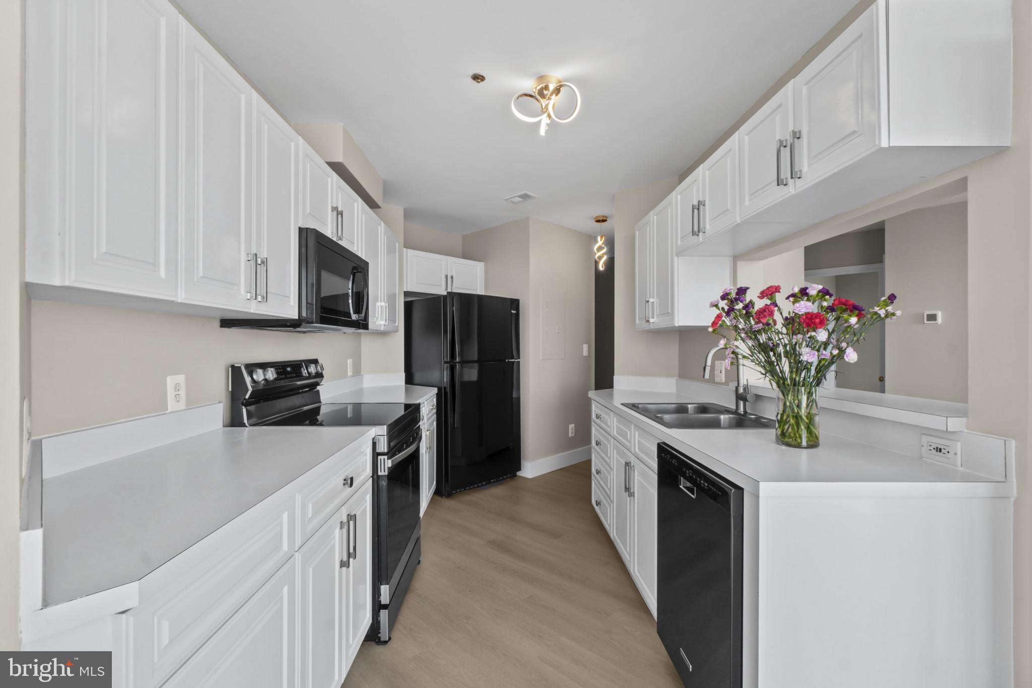 100 Harborview Drive, Unit 1312 Baltimore, MD 21230 - Photo 13 of 37 a kitchen with stainless steel appliances kitchen island granite countertop a refrigerator oven a sink dishwasher and white cabinets with wooden floor