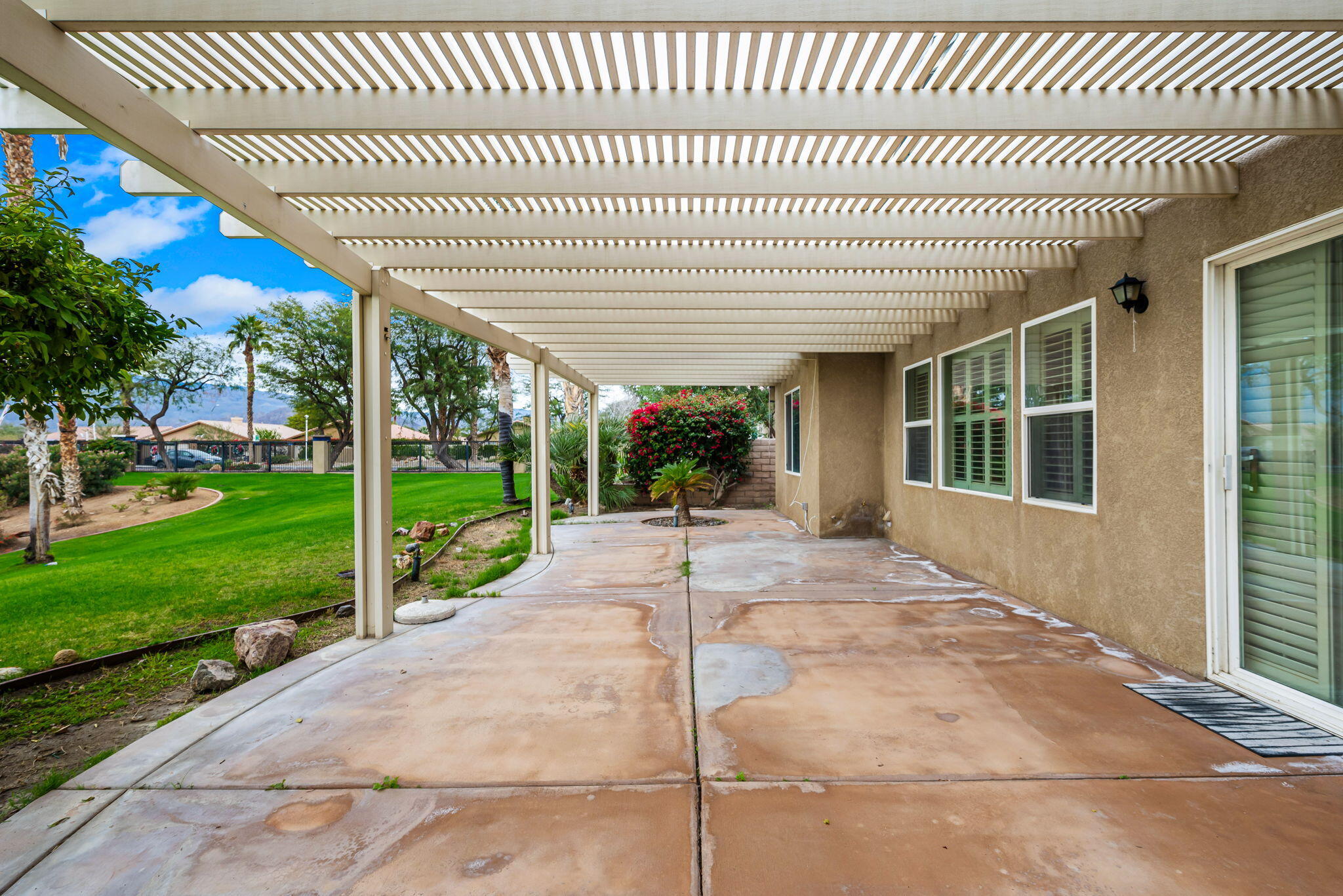 82631 Redford Way Indio, CA 92201 - Photo 39 of 43 a view of a patio with a table chairs potted plants and floor to ceiling window