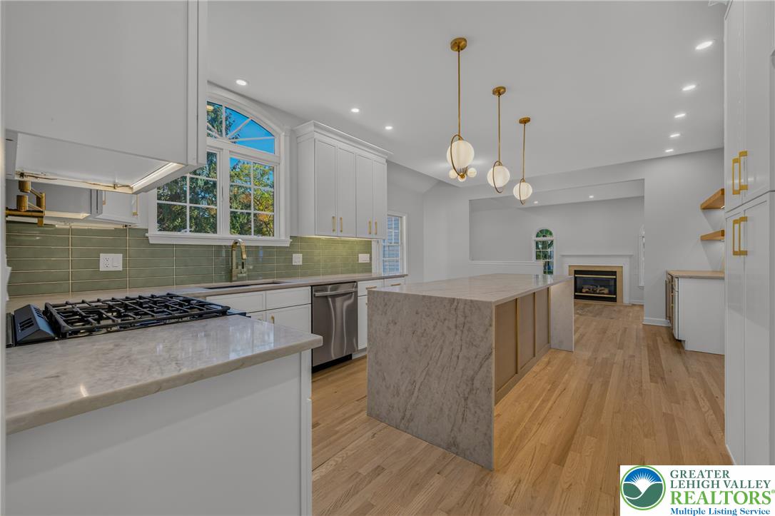 3130 Muirfield Road Center Valley, PA 18034 - Photo 25 of 63 An open kitchen layout flows seamlessly toward a fireplace-warmed living space over rich wood flooring.