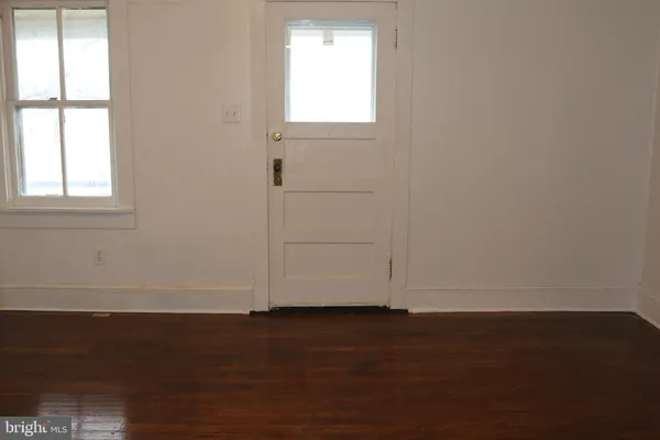 an empty room with wooden floor and windows with curtains