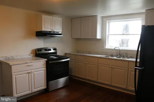 a kitchen with stainless steel appliances granite countertop white cabinets a sink and a window