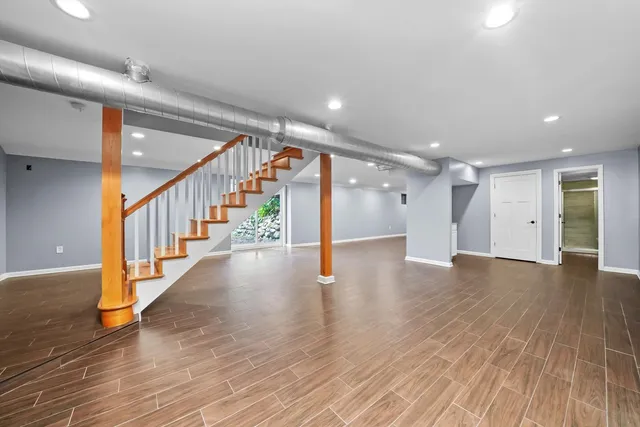 a view of an empty room with wooden floor windows and a rug