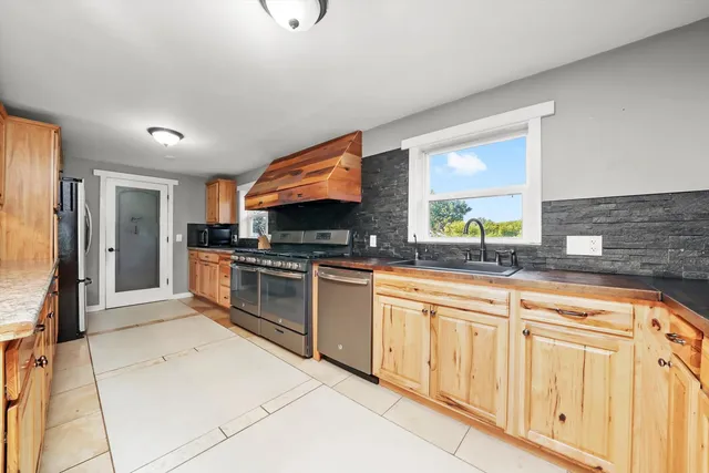 a kitchen with stainless steel appliances granite countertop a stove a sink and a refrigerator