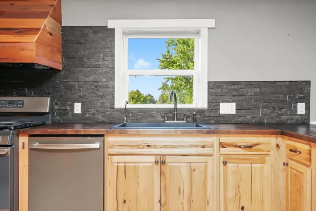 a kitchen with stainless steel appliances granite countertop a sink a counter space and a window