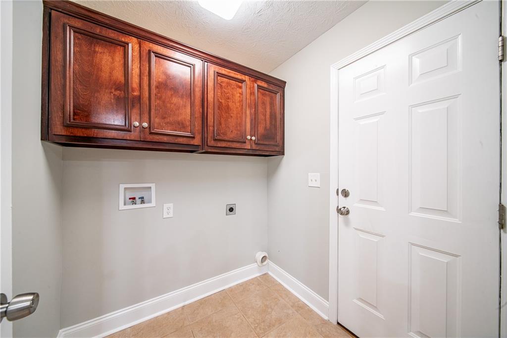 1927 Lee Road Salem, AL 36874 - Photo 28 of 45 Laundry area with hookup for an electric dryer, hookup for a washing machine, a textured ceiling, cabinet space, and light tile patterned floors