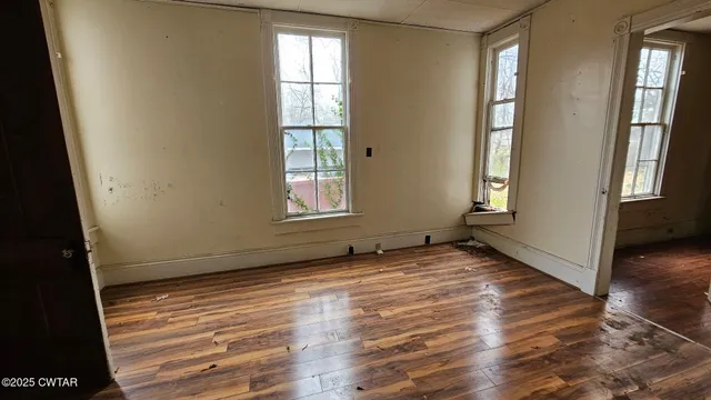 an empty room with wooden floor and windows