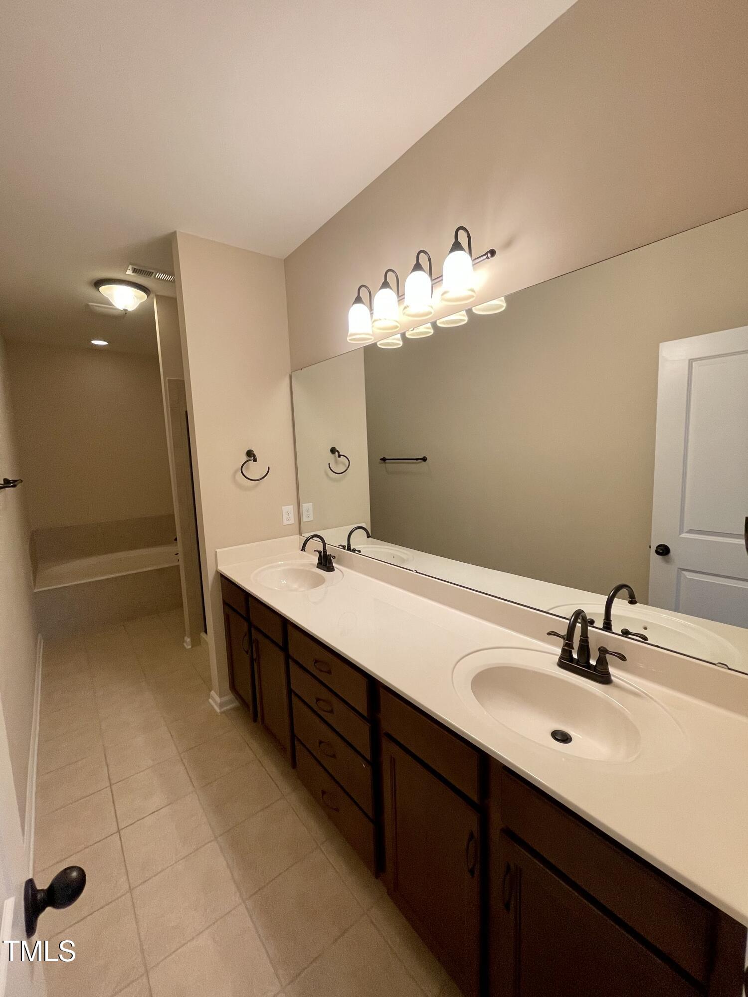 2452 Baslow Drive Apex, NC 27539 - Photo 14 of 25 a spacious bathroom with a double vanity sink and a mirror