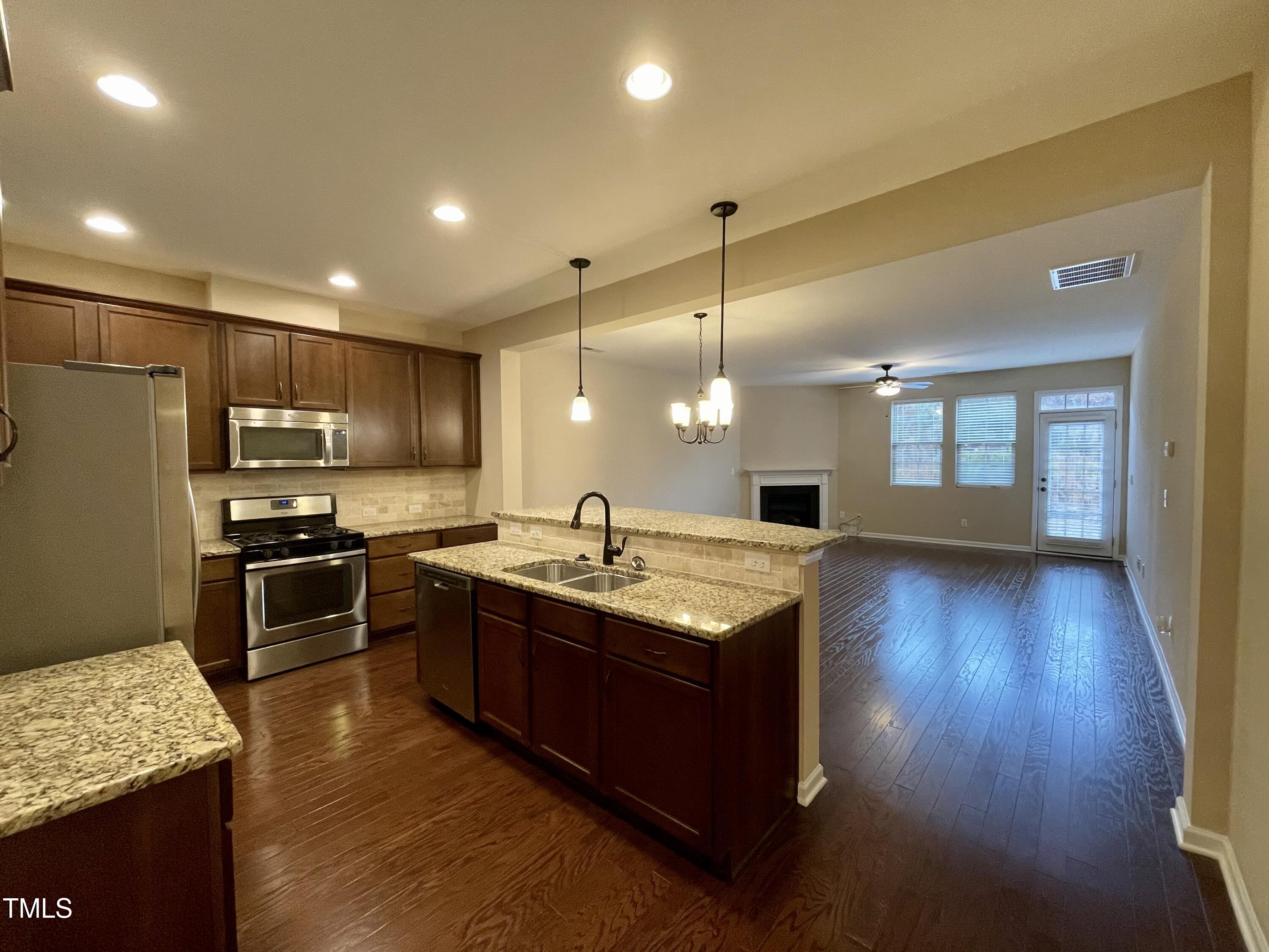 2452 Baslow Drive Apex, NC 27539 - Photo 5 of 25 a kitchen with stainless steel appliances granite countertop a stove and a wooden floors