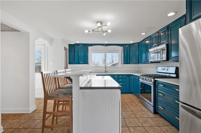 a kitchen with kitchen island granite countertop a sink a stove a refrigerator and a dining table
