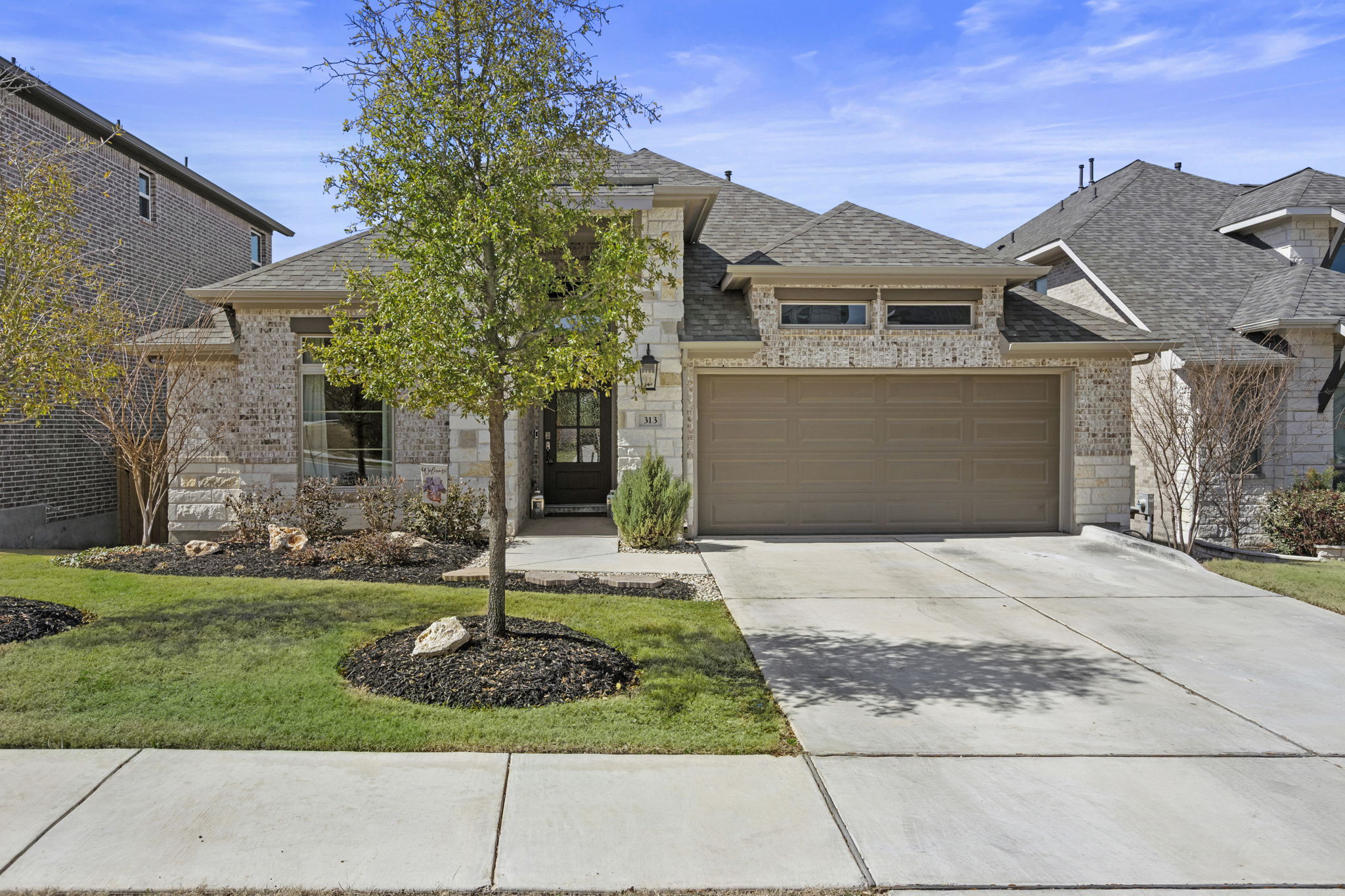 French country style house featuring driveway, a garage, a shingled roof, and stone siding