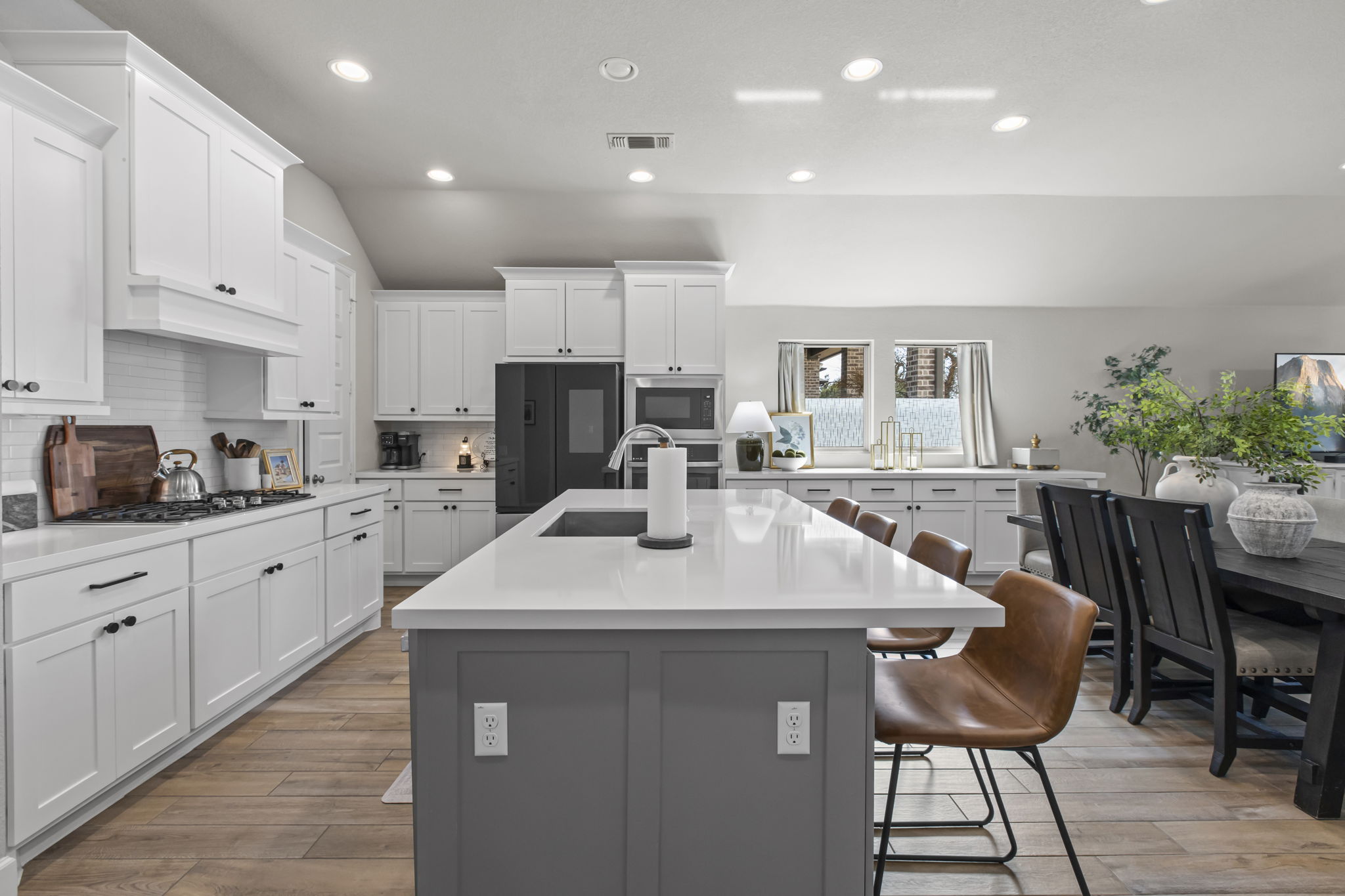 313 Terrene Trail Georgetown, TX 78628 - Photo 2 of 40 Two tone kitchen featuring lofted ceiling, an island with sink, light wood finished floors, a kitchen breakfast bar, and tasteful backsplash