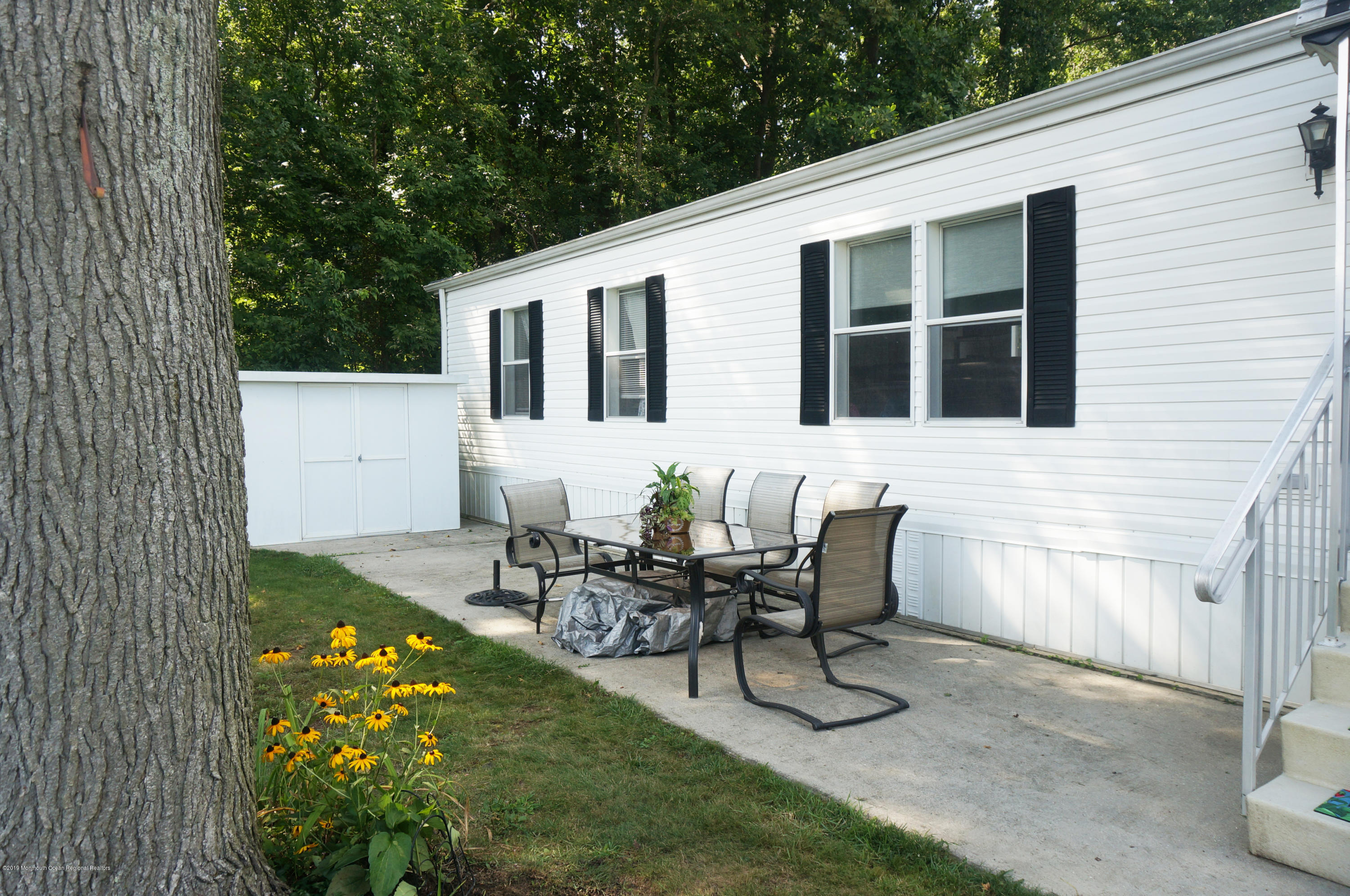 112 Woody Road Freehold, NJ 07728 - Photo 1 of 28 a view of a patio with table and chairs with wooden fence and plants