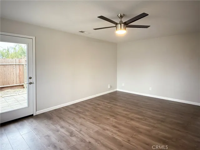 an empty room with wooden floor fan and windows