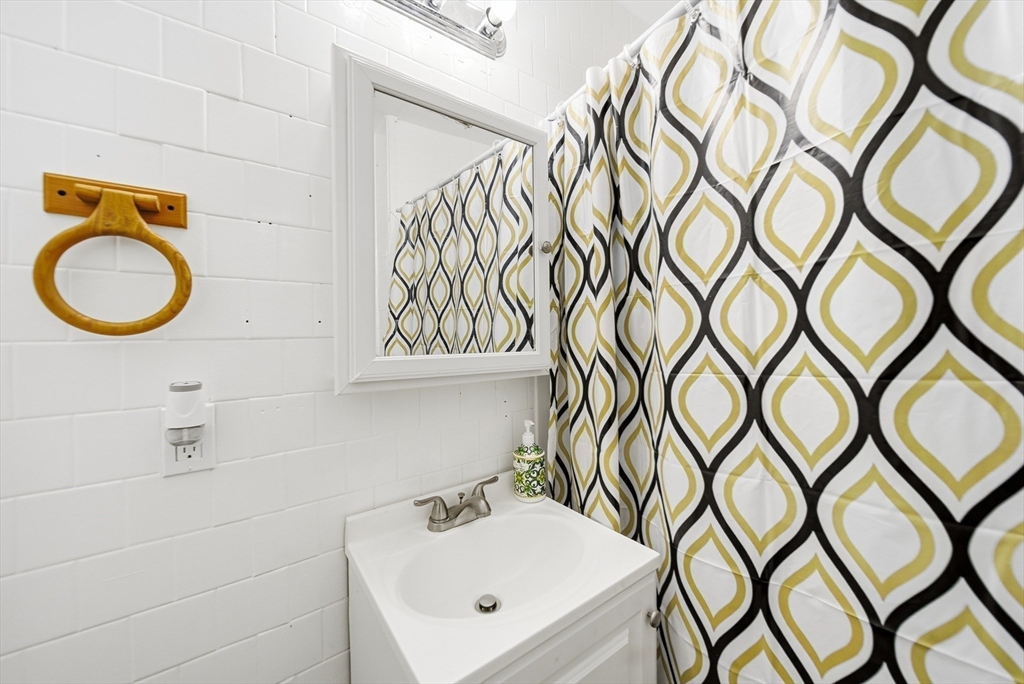 94 Sheridan Street Lynn, MA 01902 - Photo 17 of 33 a bathroom with a sink a mirror and a shower curtain