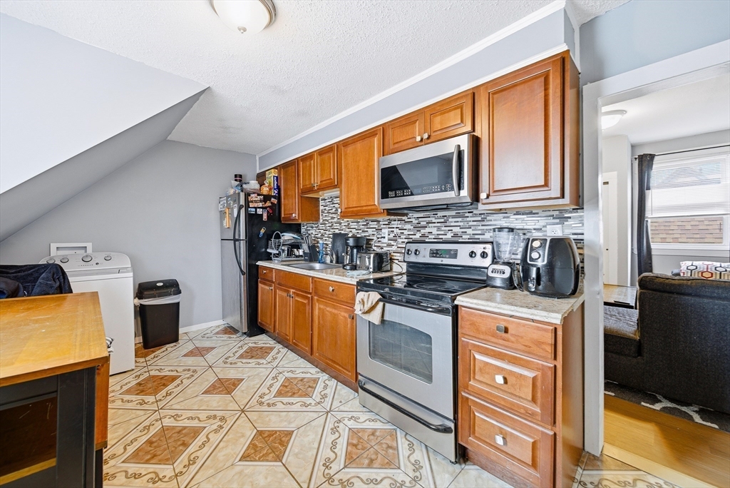 94 Sheridan Street Lynn, MA 01902 - Photo 19 of 33 a kitchen with stainless steel appliances granite countertop a stove top oven a sink dishwasher and cabinets with wooden floor