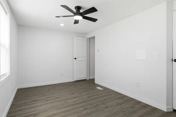 an empty room with wooden floor and windows