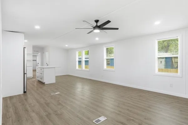 a view of an empty room with a window and wooden floor