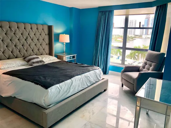 a bedroom with a bed couch and lamp next to a window