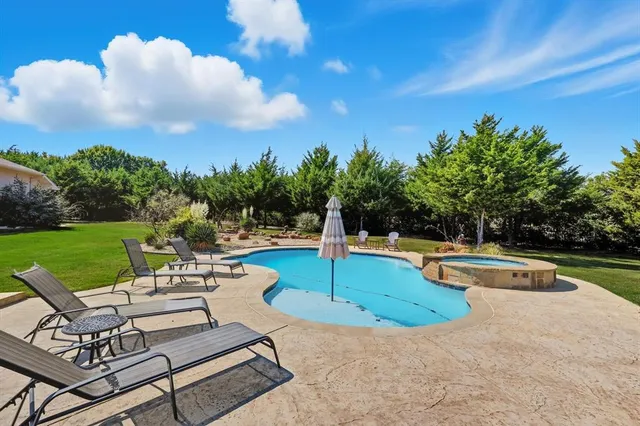 a view of a house with a big yard and potted plants and large trees