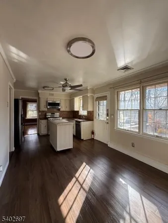 a kitchen with stainless steel appliances granite countertop a stove a sink dishwasher a refrigerator and a dining table with wooden floor