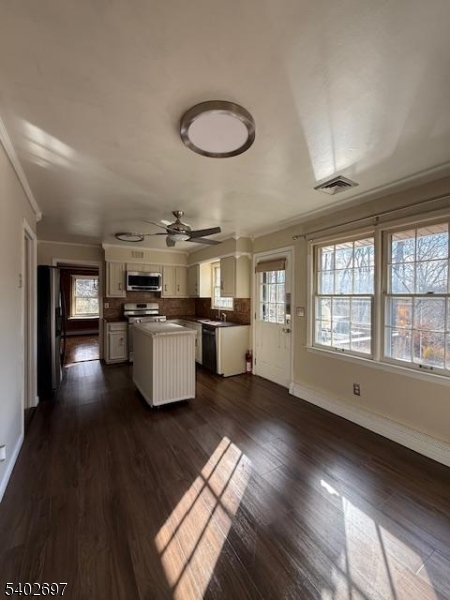 a kitchen with stainless steel appliances granite countertop a stove a sink dishwasher a refrigerator and a dining table with wooden floor