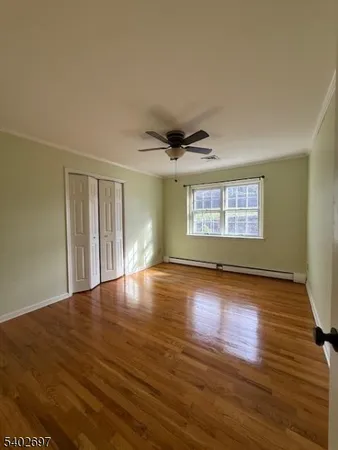 a view of an empty room with window and wooden floor