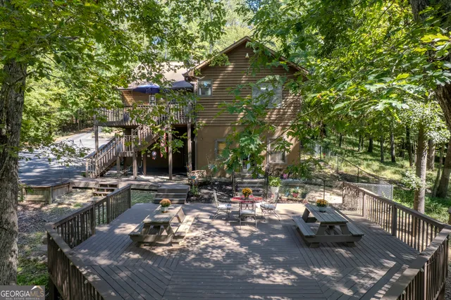 a view of a house with a deck and a yard with furniture