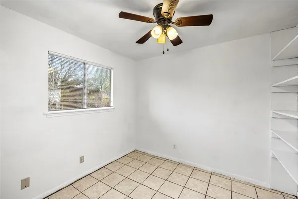 an empty room with a window and a fan